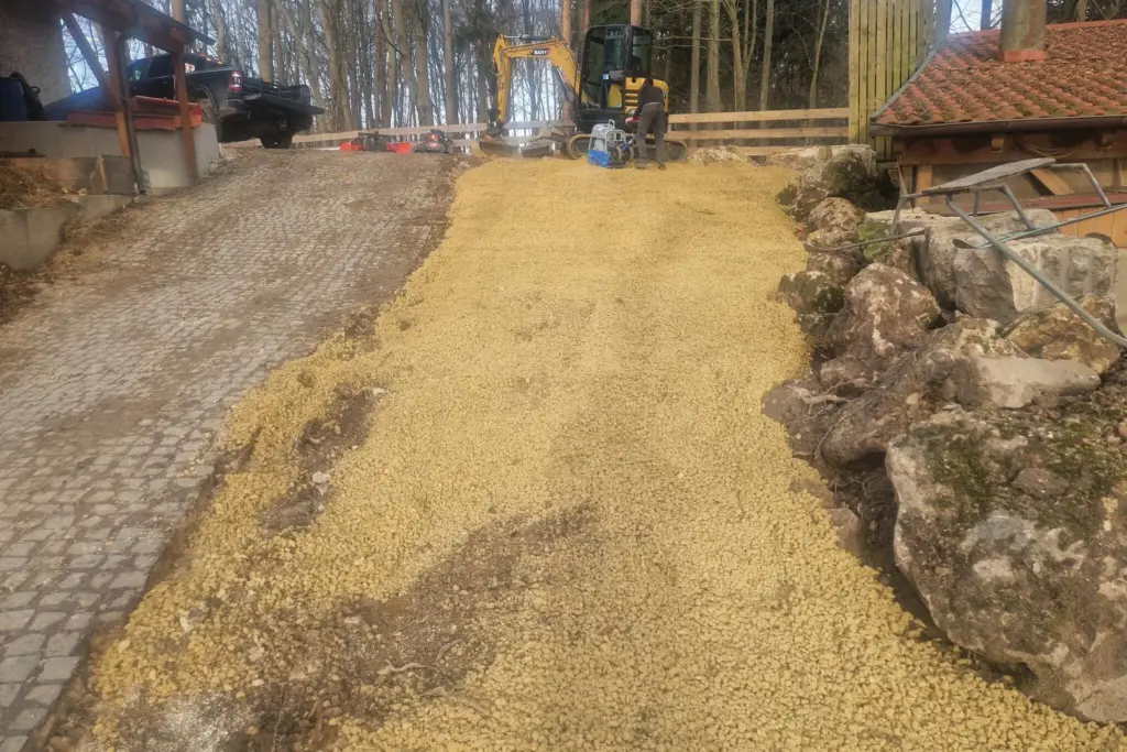 Eine sandige Auffahrt, die für das Bestücken mit Pflastersteinen vorbereitet ist.