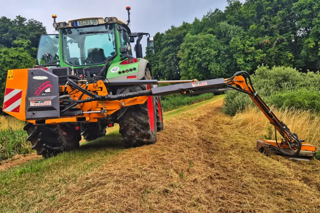 Ein Auslegemulcher am Teichdamm im Sommer auf einem Feld nahe des Waldes