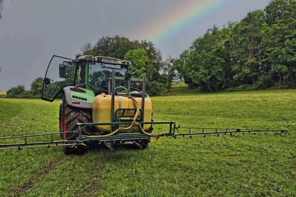 Ein grün-gelber Traktor beim chemiefreien Düngen der Felder