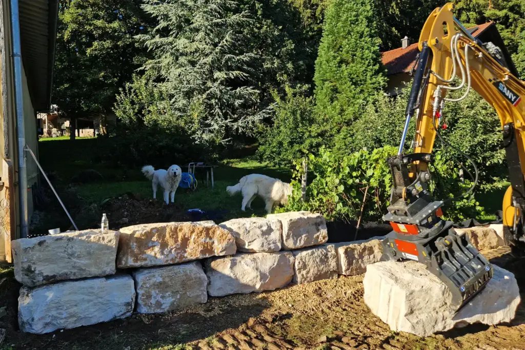 Zwei Hunde im Garten beobachten den Bau einer Natursteinmauer